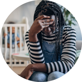 Black woman looking down toward the ground with her hand on her forehead.