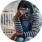 Black woman looking down toward the ground with her hand on her forehead.