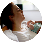 Caucasian woman looking off into the distance, holding a newborn.