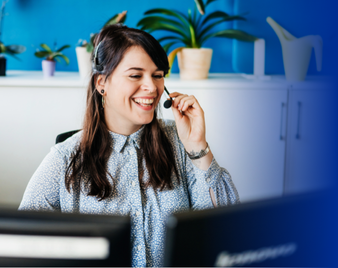 A woman speaking into headset while sitting in front of computer.