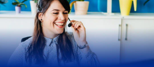 A woman speaking into headset while sitting in front of computer.